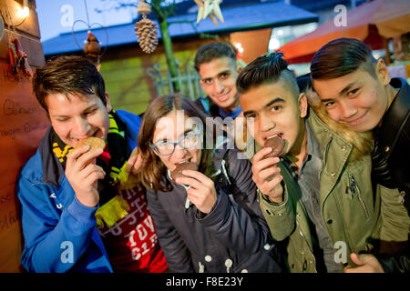 Schnaittach, Deutschland. 6. Dezember 2015. Sofia Wunner (2-L), Leiter der Caritas Wohngruppe für Flüchtlinge in Schnaittach, isst Lebkuchen mit jungen Flüchtlingen der Anlage, auf dem Weihnachtsmarkt in Schnaittach, Deutschland, 6. Dezember 2015. Rund 14.500 Jugendliche Flüchtlinge leben im deutschen Bundesland Bayern, nach dem Staatsministerium für Soziales. Die Gruppe in Schnaittach besteht aus neun muslimische Jugendliche zwischen 13 und 17 Jahren aus Syrien, Somalia und Afghanistan. Foto: DANIEL KARMANN/Dpa/Alamy Live News Stockfoto