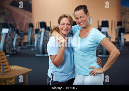 Zwei glückliche sportliche Frauen stehen in einem Fitnessstudio Stockfoto