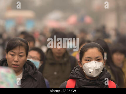 Menschen und Pendler tragen auf ihrem Weg zur Arbeit Gesichtsmasken und trotzen der starken Luftverschmutzung in der chinesischen Hauptstadt, da die Werte auf mehr als das 20-fache des Sicherheitsniveaus stiegen, was zu einer roten Warnung für ganz Peking führte. © Olli Geibel Stockfoto