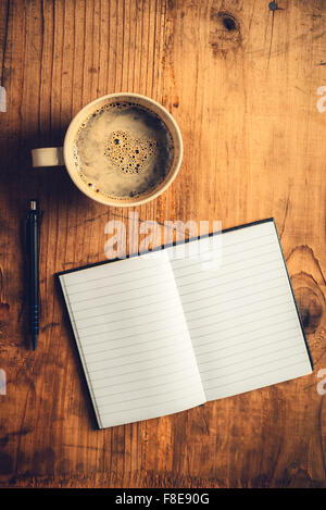 Draufsicht der offenen Notebook mit leeren Seiten, schreiben Bleistift und Tasse Kaffee auf alten hölzernen Schreibtisch, getönten Retro Bild Stockfoto