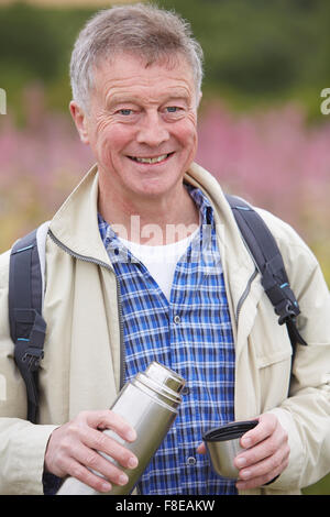 Senior woman gießen heißes Getränk aus Flasche auf Spaziergang Stockfoto