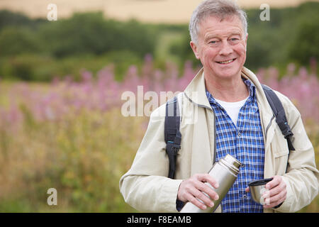 Senior woman gießen heißes Getränk aus Flasche auf Spaziergang Stockfoto