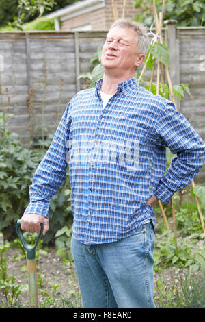 Ältere Mann unter Rückenschmerzen leiden, während im Garten Stockfoto