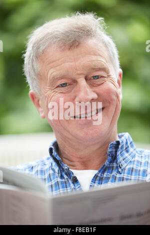 Senior woman lesen Zeitung im Freien zu Hause Stockfoto