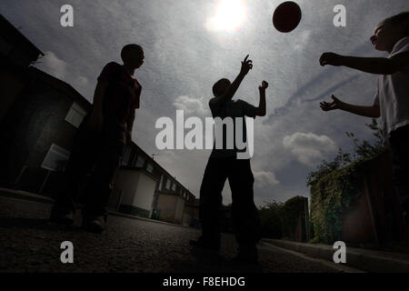 Silhouette der Kinder spielen mit einem Ball auf den Straßen in Oldham, Großbritannien Stockfoto