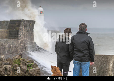 Menschen, die riesige Wellen über dem Kai und dem Leuchtturm am Meer in Porthcawl, South Wales, beobachten. Stockfoto