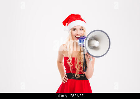 Attraktive positive junge blonde Frau im Weihnachtsmann-Kostüm sprechen im Megaphon auf weißem Hintergrund Stockfoto