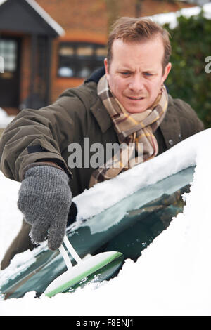 Mann, Schnee vom Auto Windschutzscheibe kratzen Stockfoto