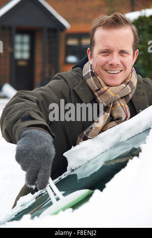 Mann, Schnee vom Auto Windschutzscheibe kratzen Stockfoto