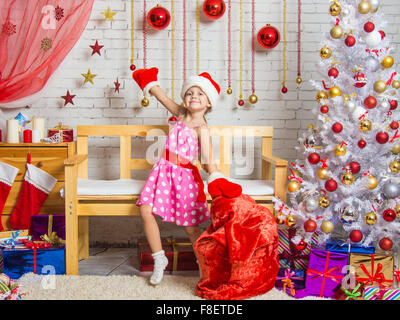 Fröhliche Mädchen spielen und Spaß mit einer Tasche von Geschenken in der Silvester-Wohngebäude Stockfoto