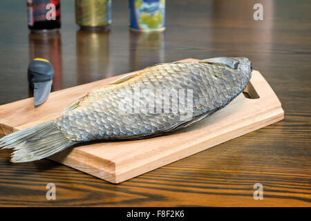 Auf dem Tisch liegt ein Cutting Board mit einem großen gesalzene und getrocknete Fisch. Nächsten Bier in Dosen. Stockfoto