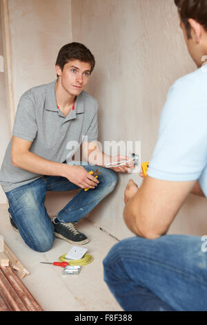 Elektriker mit Lehrling arbeitet im neuen Zuhause Stockfoto