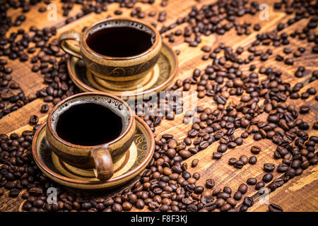 Tassen Kaffee auf Holztisch mit verstreuten Bohnen Stockfoto