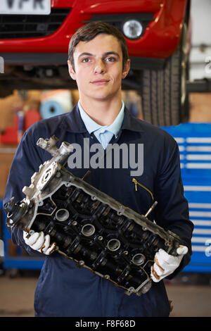 Lehrling Machanic hält Motorblock In Garage Stockfoto