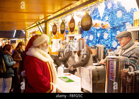Ein Mann in einem Santa Claus Kostüm kaufen Glühwein, Weihnachtsmarkt Straßburg, Straßburg Elsass Frankreich Europa Stockfoto