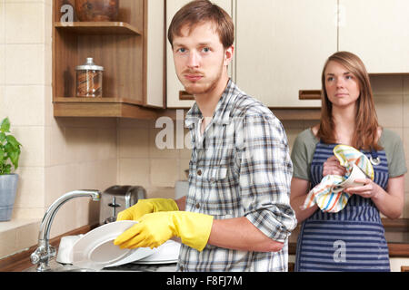 Mann, widerwillig waschen bis In die Küche mit Partner Stockfoto