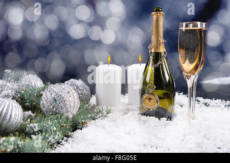 Weihnachten und neuen Jahren Champagner Feier Hintergrund mit einer Flasche und zwei Flöten Champagner im Schnee mit Tannenzweigen und silbernen Kugeln gegen einen funkelnden Bokeh Party Lichter. Stockfoto