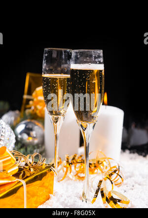 Feiern Weihnachten und Neujahr mit zwei Gläsern auf Schnee mit brennenden Kerzen Advent und goldenen Luxusgeschenke, dunklen Hintergrund mit Exemplar romantische Champagner steht. Stockfoto