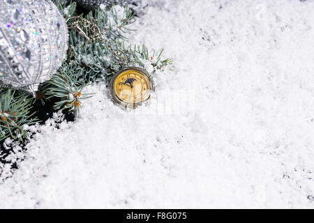 High Angle View of Antike Taschenuhr im Schnee neben immergrünen Zweige liegend verziert mit Silber Weihnachtskugeln - festlichen Stillleben mit Textfreiraum. Stockfoto