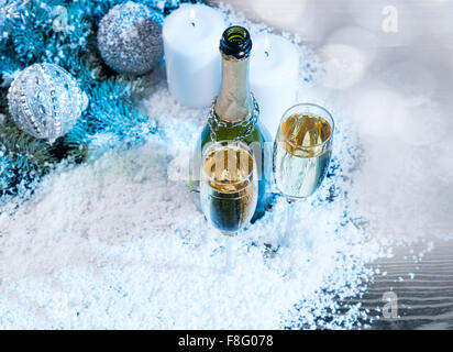 High Angle festliche Weihnachten Stillleben mit textfreiraum - zwei Gläser Champagner mit offenen Flasche auf Oberfläche bestäubt mit gefälschten Schnee und akzentuiert mit blauen und silbernen Verzierungen und Kerzen angezündet. Stockfoto