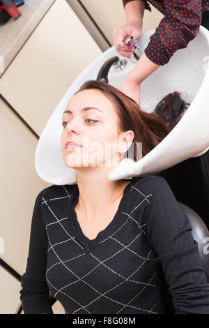 Close Up High Angle View of junge Brünette Frau, die Haare gewaschen von Stylistin in spezielle Haarwäsche Waschbecken im Salon Stockfoto