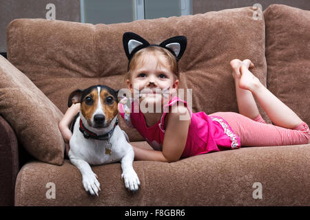 kleines Mädchen mit Katze Kinderschminken umarmen ihr Hund Stockfoto