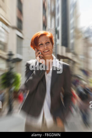 Kaukasische Geschäftsfrau, reden über Handy in Stadt Stockfoto