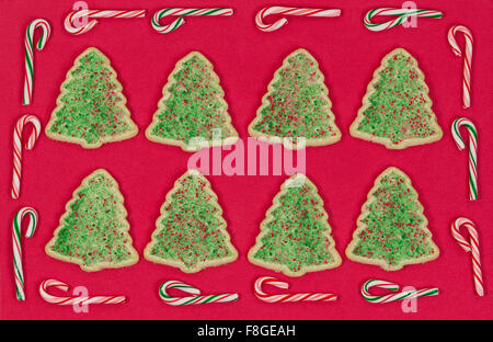 Weihnachtsbaum geformt Cookies auf rotem Grund mit Candy Cane Grenze organisiert. Stockfoto