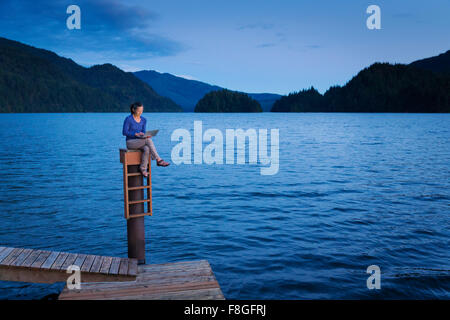 Japanische Frau sitzen auf hölzerne Dock am See Stockfoto