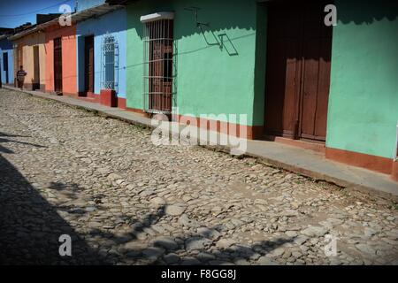 lokale Frau geht durch die typischen bunten Häusern im Kolonialstil auf einer sonnigen gepflasterten Straße in Trinidad Provinz Sancti Spiritus-Kuba Stockfoto