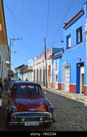 dunkle rote Hillman Oldtimer Parken im Schatten und Fußgänger zu Fuß in einer bunten gepflasterten Straße in Trinidad Kuba Stockfoto