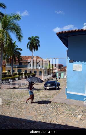 Kubanische Frauen zu Fuß mit einem Regenschirm in der Sonne auf der Plaza Mayor in Trinidad Provinz Sancti Spiritus-Kuba Stockfoto