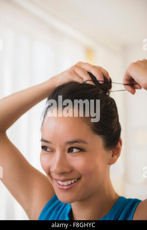 Chinesische Frau binden ihre Haare in Brötchen Stockfoto