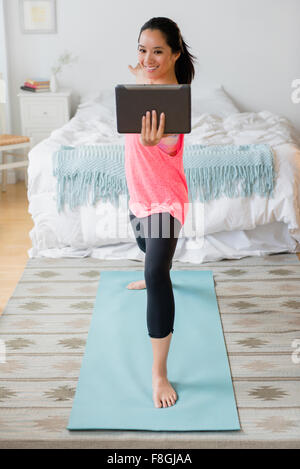 Chinesische Frau praktizieren Yoga mit digital-Tablette Stockfoto