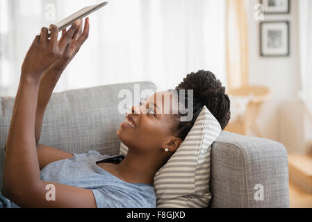 Schwarze Frau mit digital-Tablette auf sofa Stockfoto