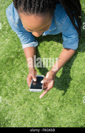 Schwarze Frau mit Handy-Gras Stockfoto