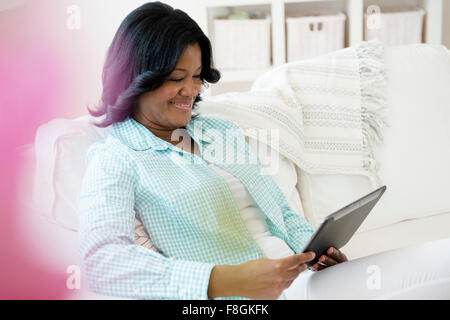 Schwarze Frau mit digital-Tablette auf sofa Stockfoto