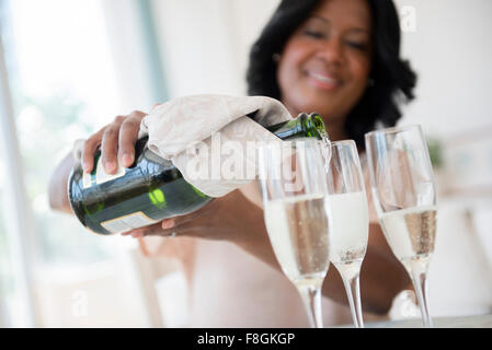 Schwarze Frau Gläser Champagner in Strömen Stockfoto