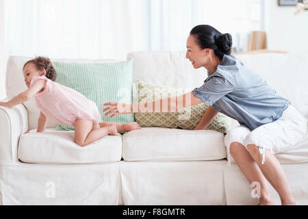 Mutter und Baby Tochter spielen auf sofa Stockfoto