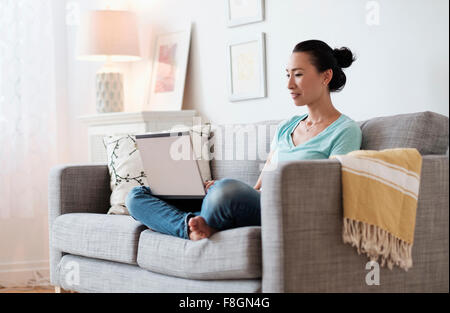 Japanische Frau mit Laptop auf sofa Stockfoto