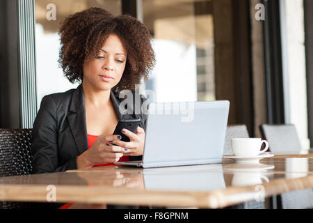 Gemischte Rassen Frau mit Handy im café Stockfoto