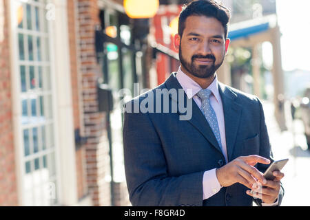Indischer Geschäftsmann mit Handy in Stadt Stockfoto