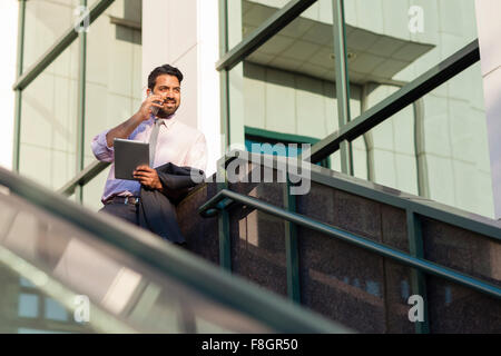 Indischer Geschäftsmann reden über Handy auf Treppe Stockfoto