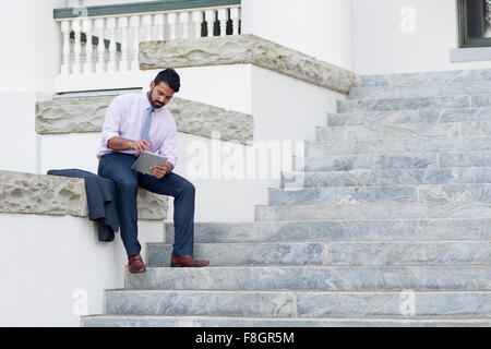 Indischer Geschäftsmann mit digital-Tablette auf Schritte Stockfoto