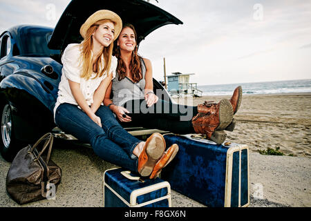 Frauen mit Gepäck und Vintage Auto am Strand Stockfoto