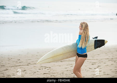 Kaukasische Surfer mit Surfbrett am Strand Stockfoto