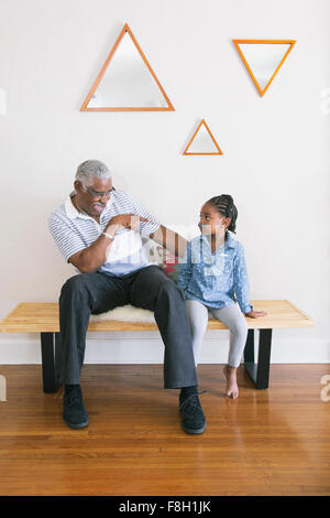 African American Großvater zeigte auf Enkelin auf Bank Stockfoto