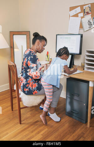 African American Mutter mit Tochter von zu Hause aus arbeiten Stockfoto