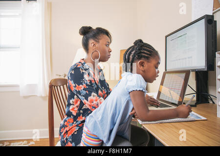 African American Mutter mit Tochter von zu Hause aus arbeiten Stockfoto