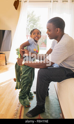 African American Vater hilft Tochter Kostüm anziehen Stockfoto